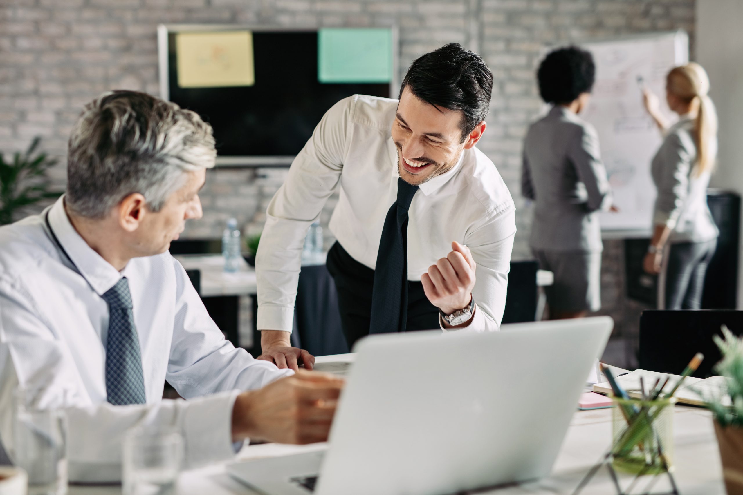 Young happy businessman communicating with his male colleague at work.